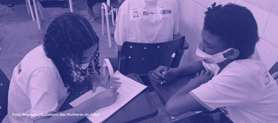 Imagem de "Centro das Mulheres do Cabo, com apoio do Fundo Malala, lança pesquisa evasão escolar de meninas e jovens mulheres", matéria no site Gênero e Educação. Duas garotas aparecem estudando